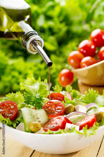 Photo: olive oil pouring over salad olive oil pouring over salad