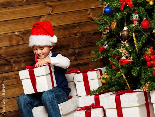 Photo: Little boy with gift box under christmas tree Little boy with gift box under christmas tree