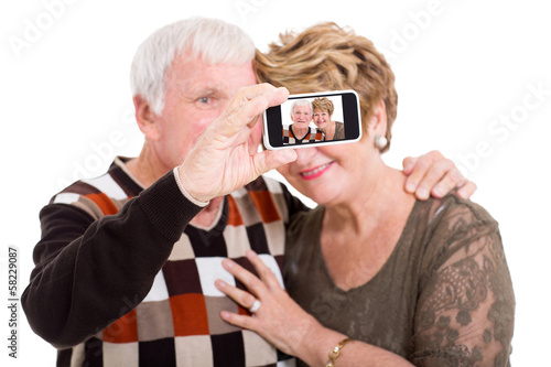 Photo: senior couple taking self portrait with smart phone senior couple taking self portrait with smart phone