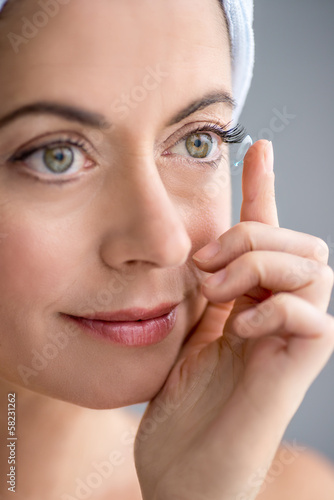 Photo: woman in her forties inserting contact lenses woman in her forties inserting contact lenses