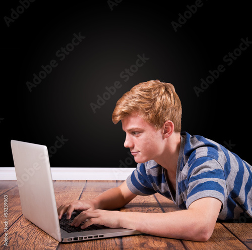 Photo: teenager auf Holzboden liegend mit Laptop teenager auf Holzboden liegend mit Laptop