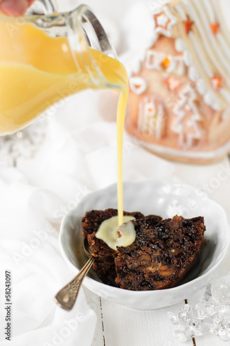 Photo: Pieces of Christmas pudding in a bowl with brandy custard, copy Pieces of Christmas pudding in a bowl with brandy custard, copy