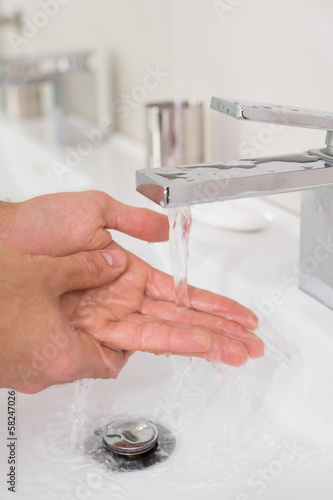 Photo: Washing hands under running water at bathroom sink Washing hands under running water at bathroom sink