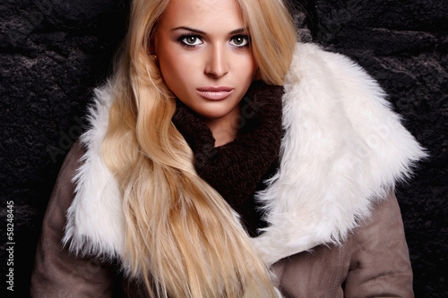 Photo: Beautiful blond woman in a fur near bricks wall. winter fashion Beautiful blond woman in a fur near bricks wall. winter fashion