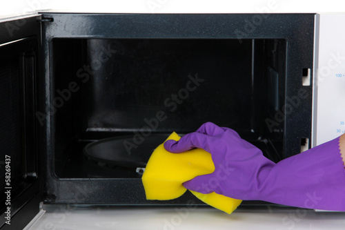 Photo: Hand with sponge cleaning microwave oven, isolated on white Hand with sponge cleaning microwave oven, isolated on white