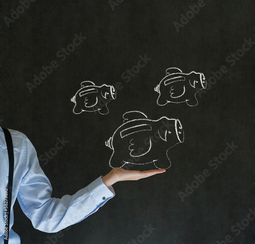 Photo: Businessman holding chalk flying piggy banks on blackboard Businessman holding chalk flying piggy banks on blackboard