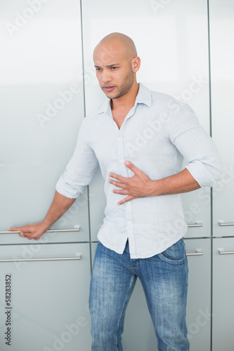 Photo: Casual young man with stomach pain at home Casual young man with stomach pain at home