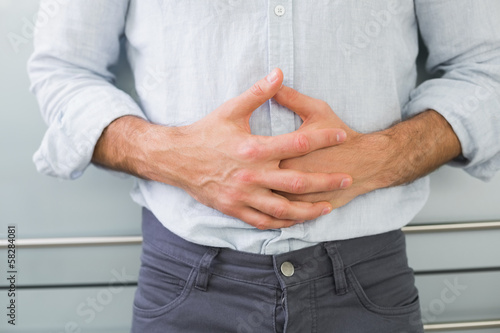 Photo: Mid section of a man suffering from stomach pain Mid section of a man suffering from stomach pain
