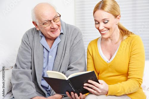 Photo: Frau liest Senior Geschichten aus Buch vor Frau liest Senior Geschichten aus Buch vor