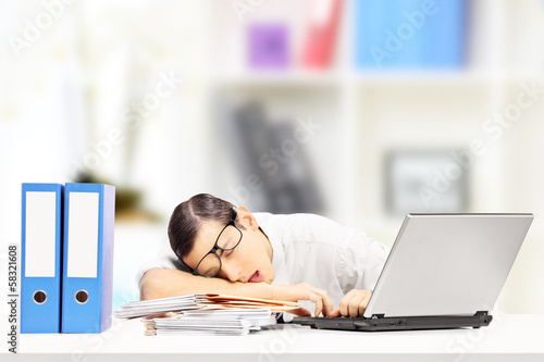 Photo: Exhausted businessman sleeping on a desk in his office Exhausted businessman sleeping on a desk in his office