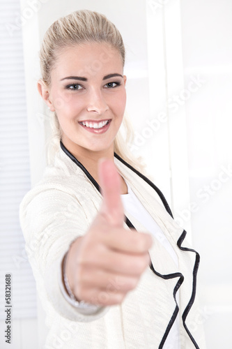 Photo: Erfolgreiche blonde junge Frau im Büro mit Daumen hoch Erfolgreiche blonde junge Frau im Büro mit Daumen hoch
