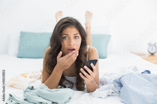 Photo: Shocked woman with mobile phone in bed Shocked woman with mobile phone in bed