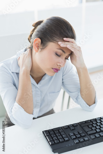 Photo: Businesswoman suffering from headache in front of laptop Businesswoman suffering from headache in front of laptop