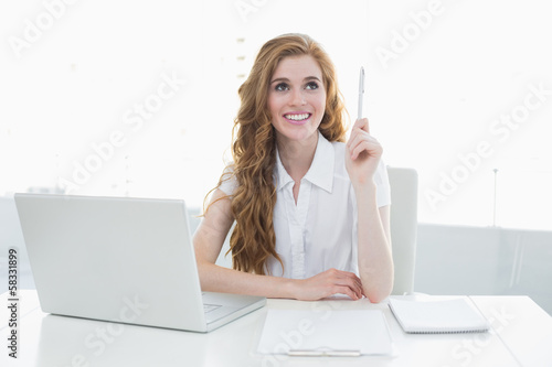 Photo: Beautiful businesswoman with laptop pointing upwards Beautiful businesswoman with laptop pointing upwards