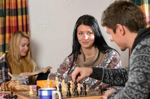 Photo: Young couple play chess winter cottage countryside Young couple play chess winter cottage countryside