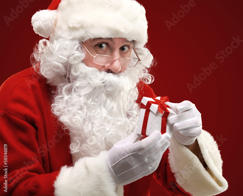 Photo: happy Santa Claus looking into white giftbox in isolation happy Santa Claus looking into white giftbox in isolation