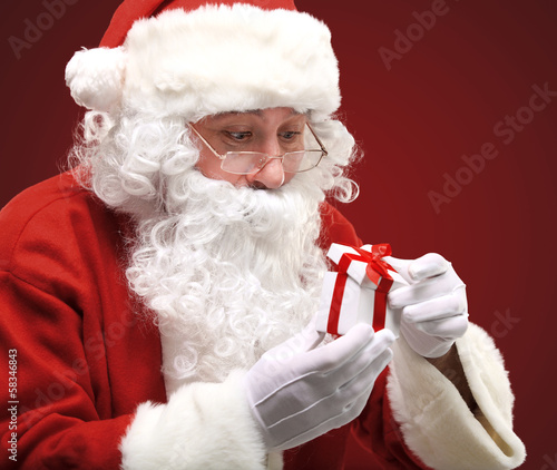 Photo: happy Santa Claus looking into white giftbox in isolation happy Santa Claus looking into white giftbox in isolation