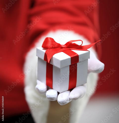 Photo: Photo of Santa Claus gloved hands holding white giftbox Photo of Santa Claus gloved hands holding white giftbox