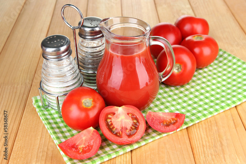 Photo: Tomato juice in glass jug, on wooden background Tomato juice in glass jug, on wooden background