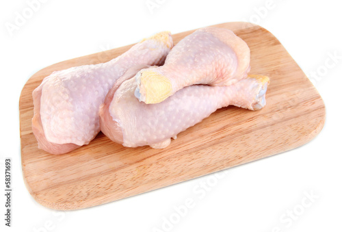 Photo: Raw chicken legs on wooden board isolated on white Raw chicken legs on wooden board isolated on white