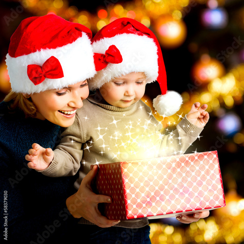 Photo: Mother with little child opens the box with gifts on christmas Mother with little child opens the box with gifts on christmas