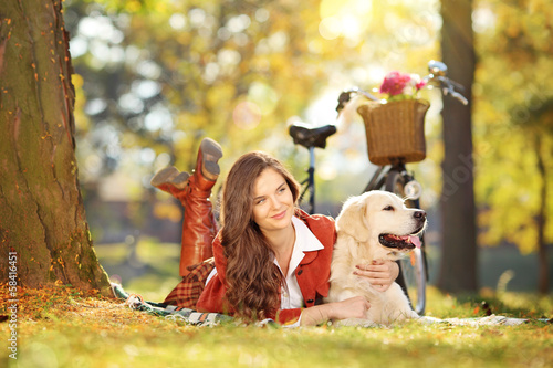 Photo: Young beautiful female on grass with her dog in a park Young beautiful female on grass with her dog in a park