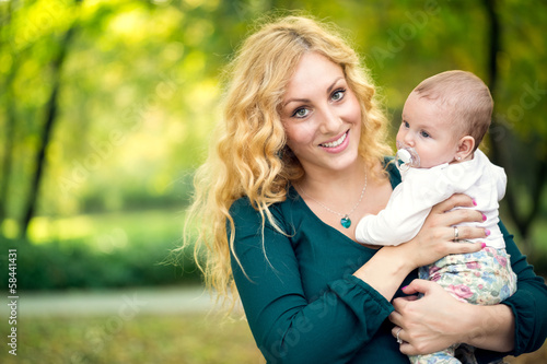 Photo: Mother with baby outdoor in green park Mother with baby outdoor in green park