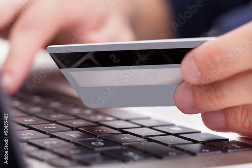 Photo: Person Holding Credit Card Using Laptop Person Holding Credit Card Using Laptop