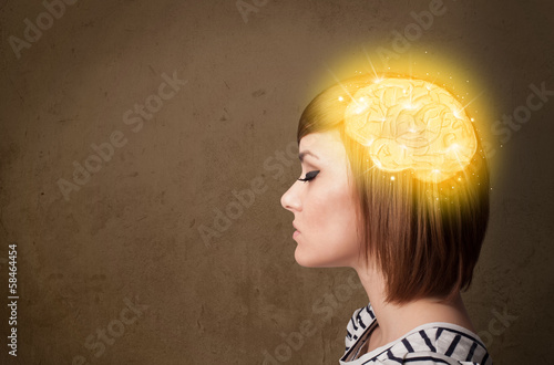 Photo: Young girl thinking with glowing brain illustration Young girl thinking with glowing brain illustration
