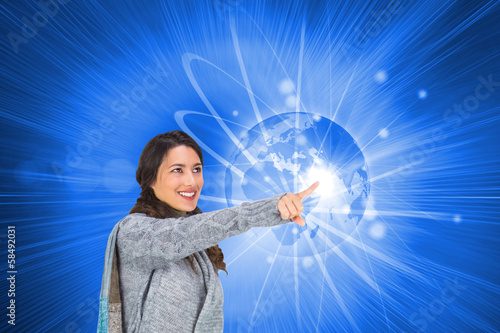 Photo: Composite image of smiling brunette wearing winter clothes point Composite image of smiling brunette wearing winter clothes point