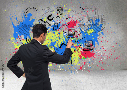 Photo: Composite image of unsmiling asian businessman pointing Composite image of unsmiling asian businessman pointing
