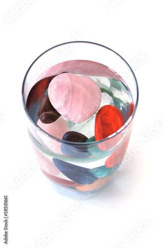 Photo: Crystals in full filled glass of water, on white, top view Crystals in full filled glass of water, on white, top view