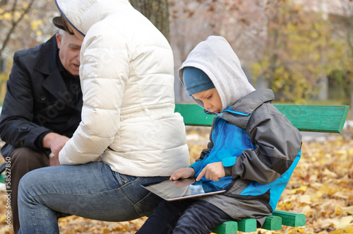 Photo: Cute little boy surfing the internet on his tablet Cute little boy surfing the internet on his tablet