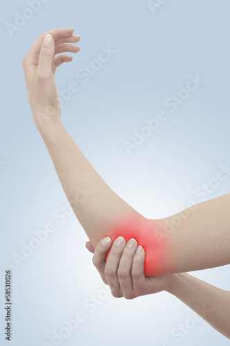 Photo: Acute pain in a woman elbow. Female holding hand to spot of elbo Acute pain in a woman elbow. Female holding hand to spot of elbo