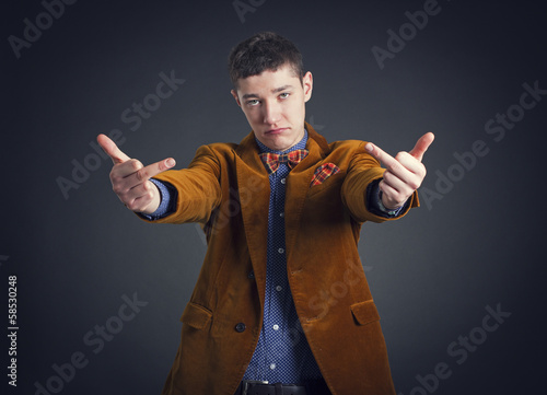 Photo: Portrait of a young man with an obscene hand gesture. Portrait of a young man with an obscene hand gesture.