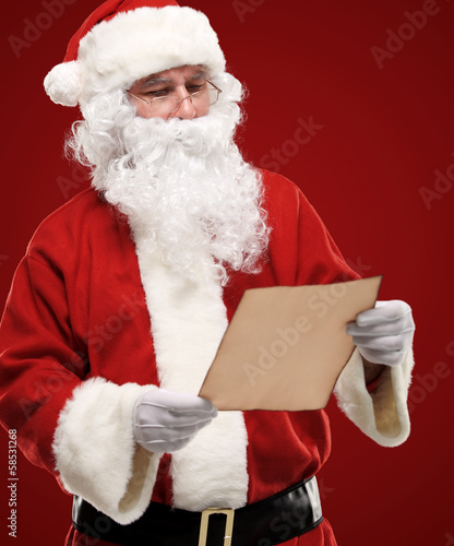 Photo: Portrait of happy Santa Claus holding Christmas letter Portrait of happy Santa Claus holding Christmas letter