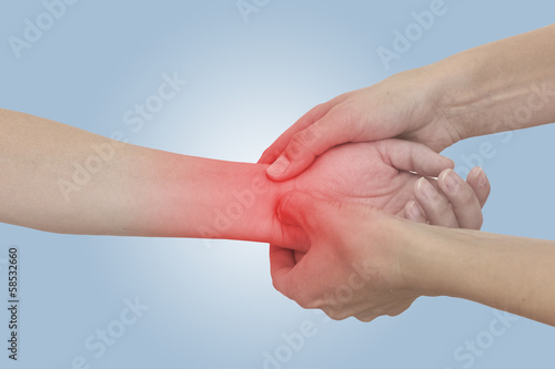 Photo: Acute pain in a woman wrist. Female holding hand to spot of wris Acute pain in a woman wrist. Female holding hand to spot of wris