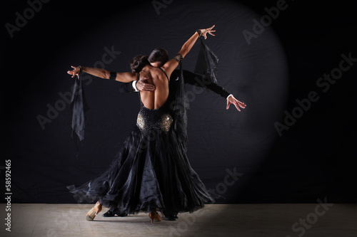 Photo: Latino dancers in ballroom against on black background Latino dancers in ballroom against on black background