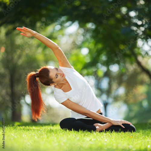 Photo: Pretty woman doing yoga exercises in the park Pretty woman doing yoga exercises in the park