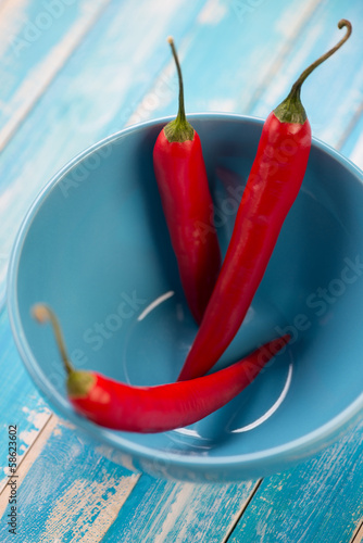 Photo: Blue bowl with red chili peppers, vertical shot, close-up Blue bowl with red chili peppers, vertical shot, close-up