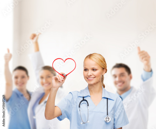 Photo: smiling doctor or nurse drawing red heart smiling doctor or nurse drawing red heart