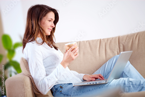 Photo: Young woman at home with laptop Young woman at home with laptop