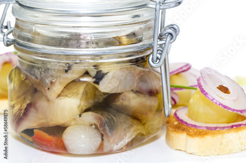 Photo: pickled herring in a glass jar with potato canapes pickled herring in a glass jar with potato canapes