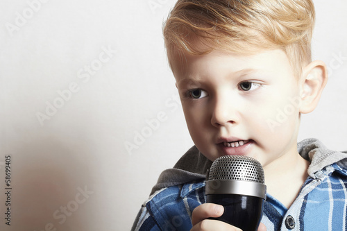 Photo: little boy singing into a microphone. child in karaoke little boy singing into a microphone. child in karaoke