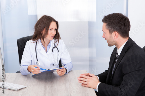 Photo: Female Doctor Looking At Businessman Female Doctor Looking At Businessman