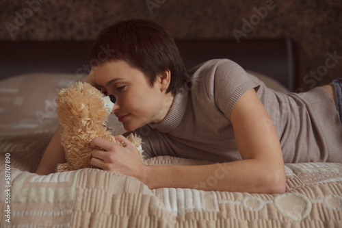 Photo: Girl lying on the bed with a teddy bear Girl lying on the bed with a teddy bear