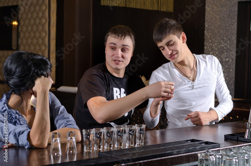 Photo: Two men chatting up a woman at the bar Two men chatting up a woman at the bar