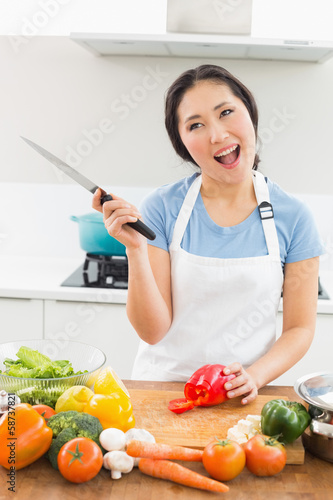 Photo: Thoughtful smiling woman chopping vegetables in kitchen Thoughtful smiling woman chopping vegetables in kitchen
