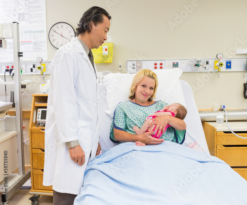 Photo: Mother Holding Newborn Babygirl While Doctor Standing By In Hosp Mother Holding Newborn Babygirl While Doctor Standing By In Hosp