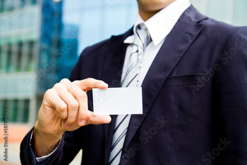 Photo: young businessman holding visit card in hand and standing in the young businessman holding visit card in hand and standing in the